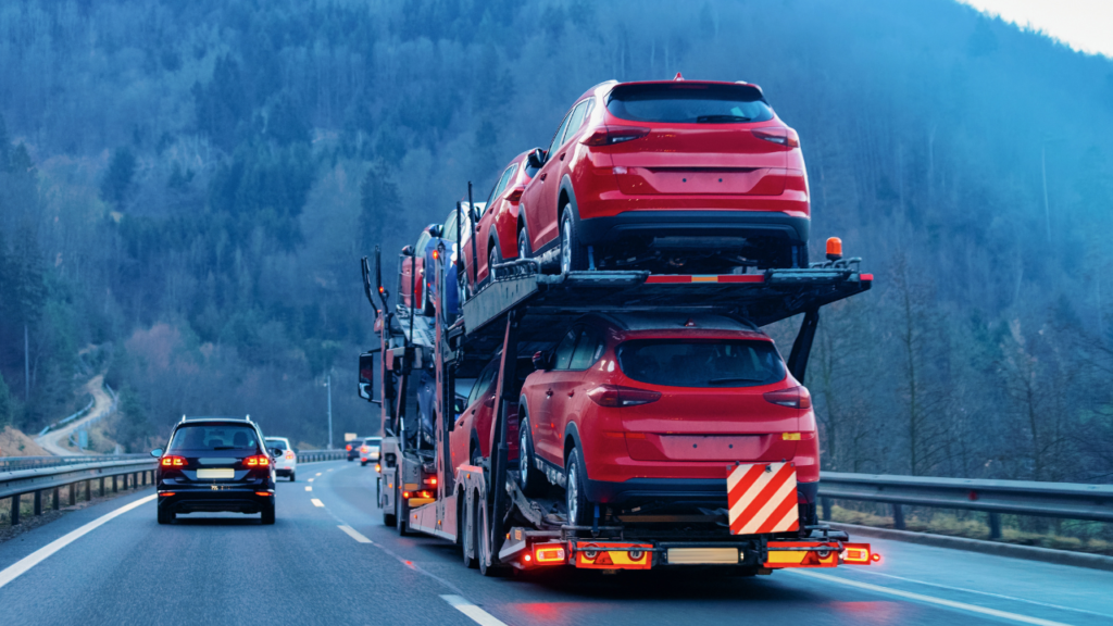 Open car transport trailer carrying multiple vehicles on the highway